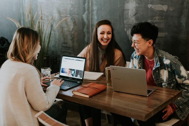 Three people working on table and laughing